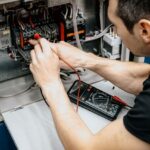 Multimetre ile elektrik panosunda ölçüm yapan elektrik teknisyeni