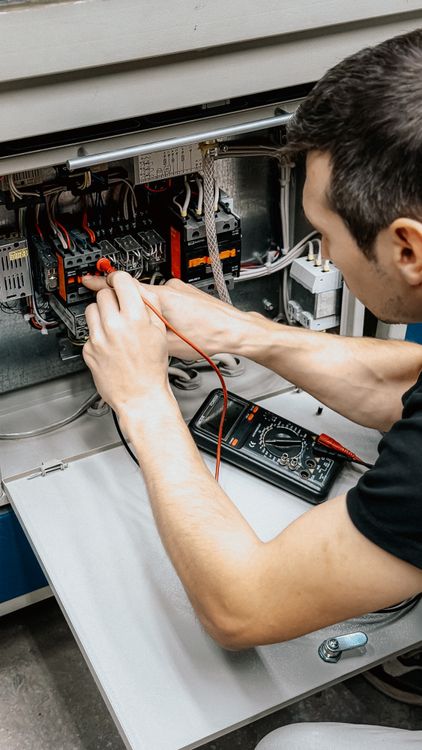 Multimetre ile elektrik panosunda ölçüm yapan elektrik teknisyeni